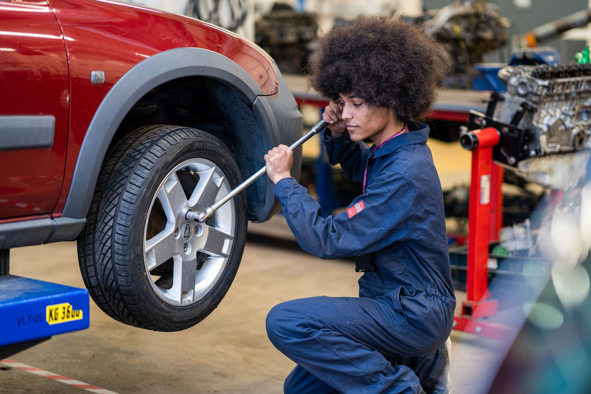 Motor Vehicle and Automotive student changing tyre in car garage