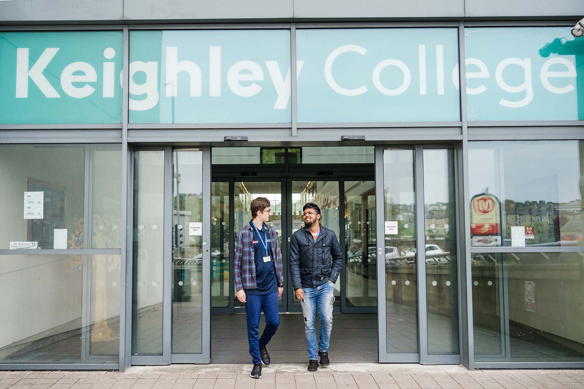 Two students standing outside the main entrance to Keighley College