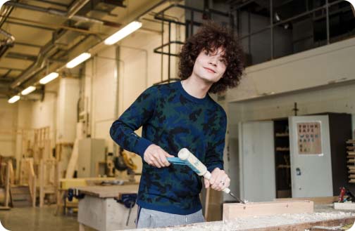 Construction student in workshop using a woodwork tool