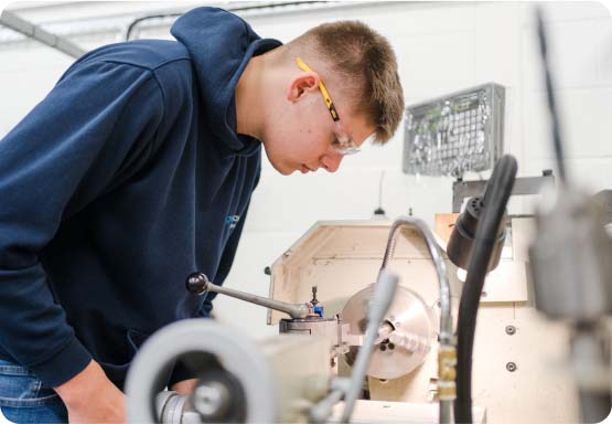 Student wearing safety goggles using machinery in the workshop at Keighley College