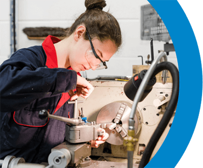 Student wearing safety goggles using machinery in workshop at Keighley College