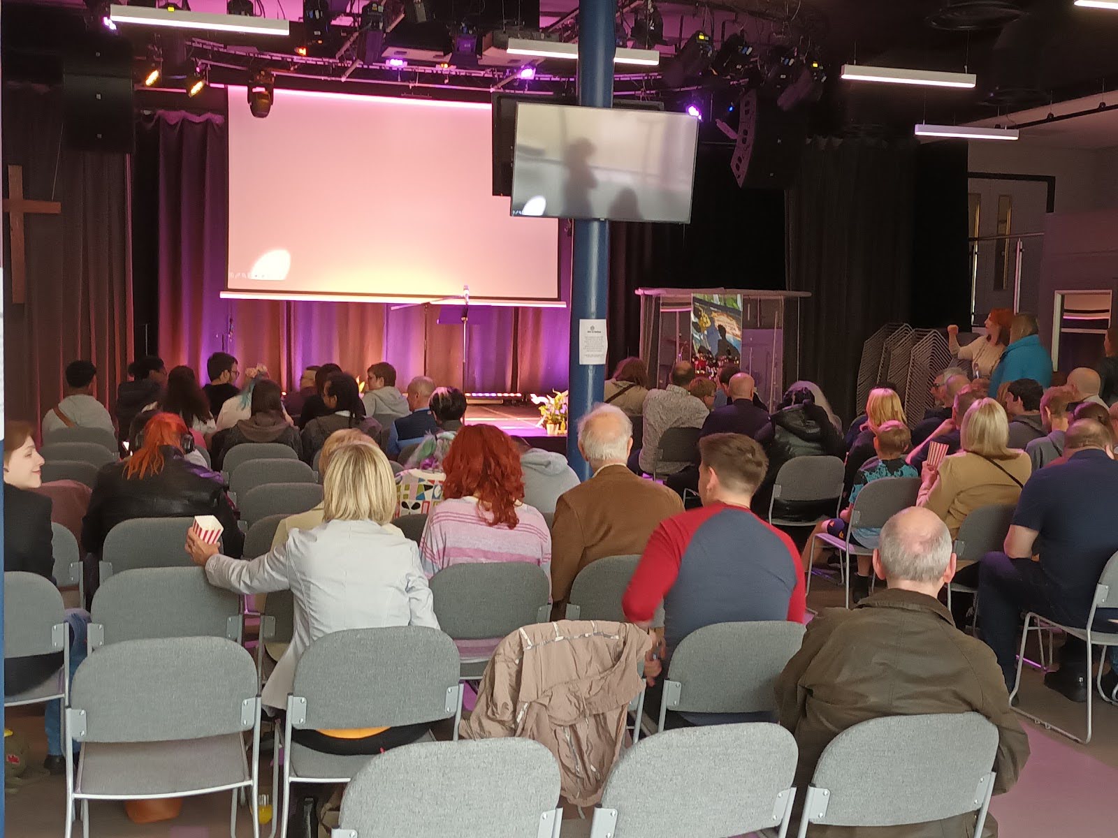 An audience seated in front of a stage in a large hall