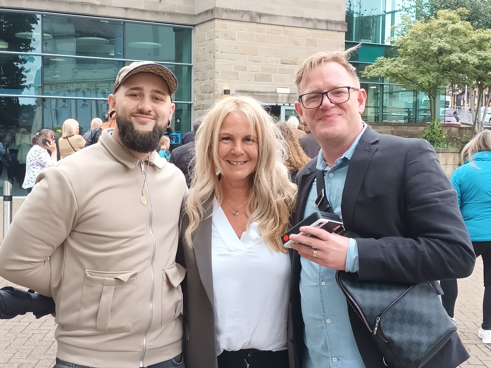 A woman stands between two gentleman as all three smile and pose for the camera