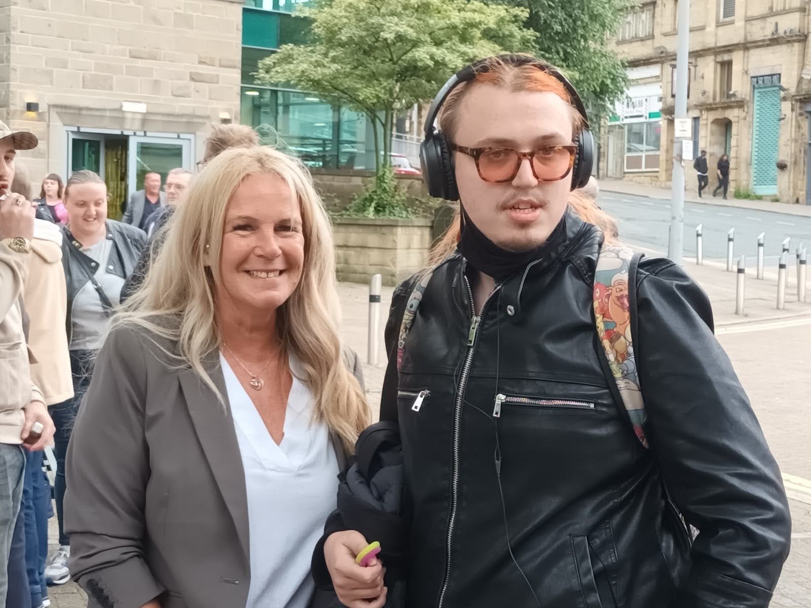 A woman and a student wearing headphones smile for the camera