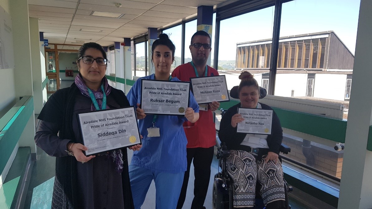 A group of people - three standing, one sat in a wheelchair - pose together holding certificates of qualification