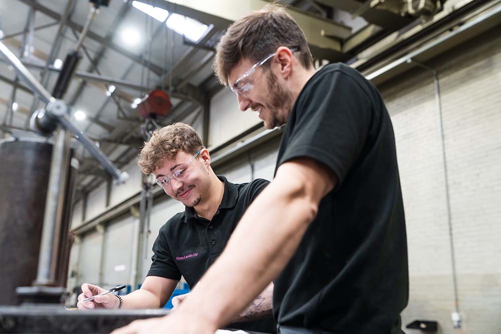 Five Landis apprentice working with employer looking down making notes wearing safety glasses