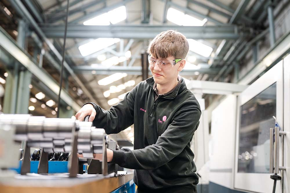 Student wearing safety goggles using machinery in the workshop at Keighley College