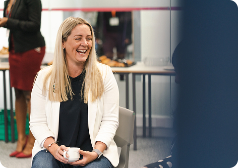 Staff member sitting on a chair drinking a coffee