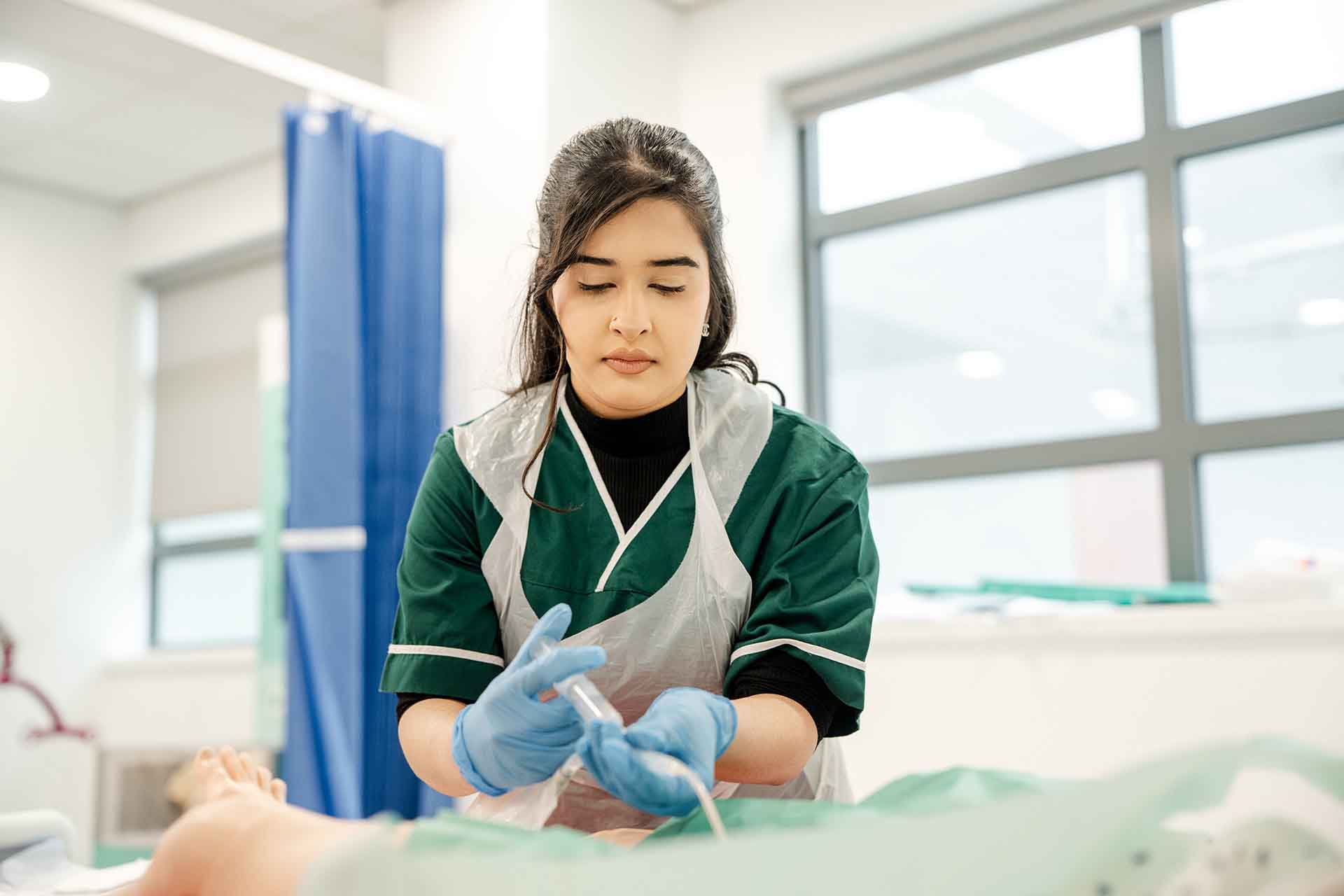 Healthcare student wearing uniform and gloves practicing injection techniques