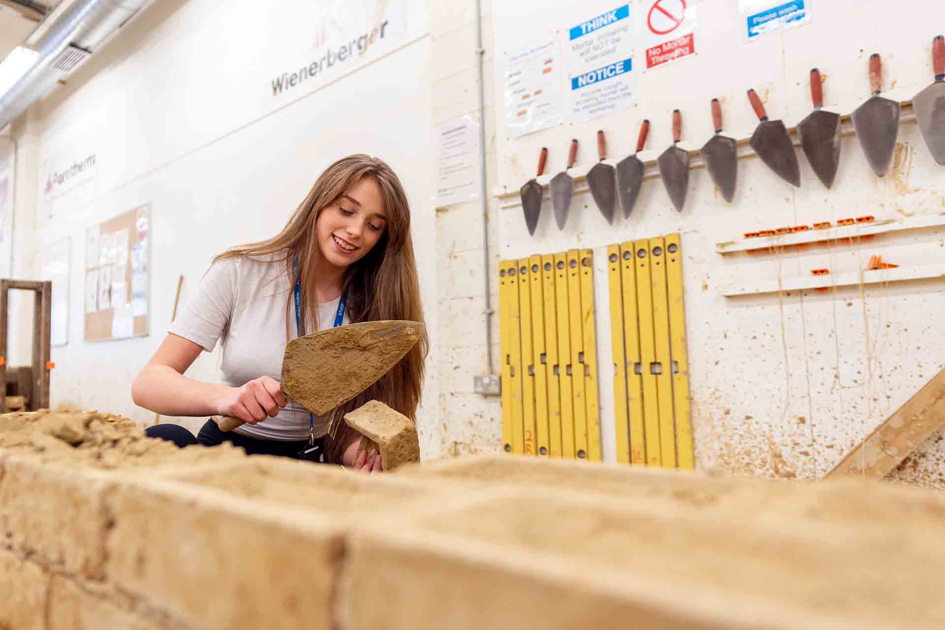 Construction student laying bricks